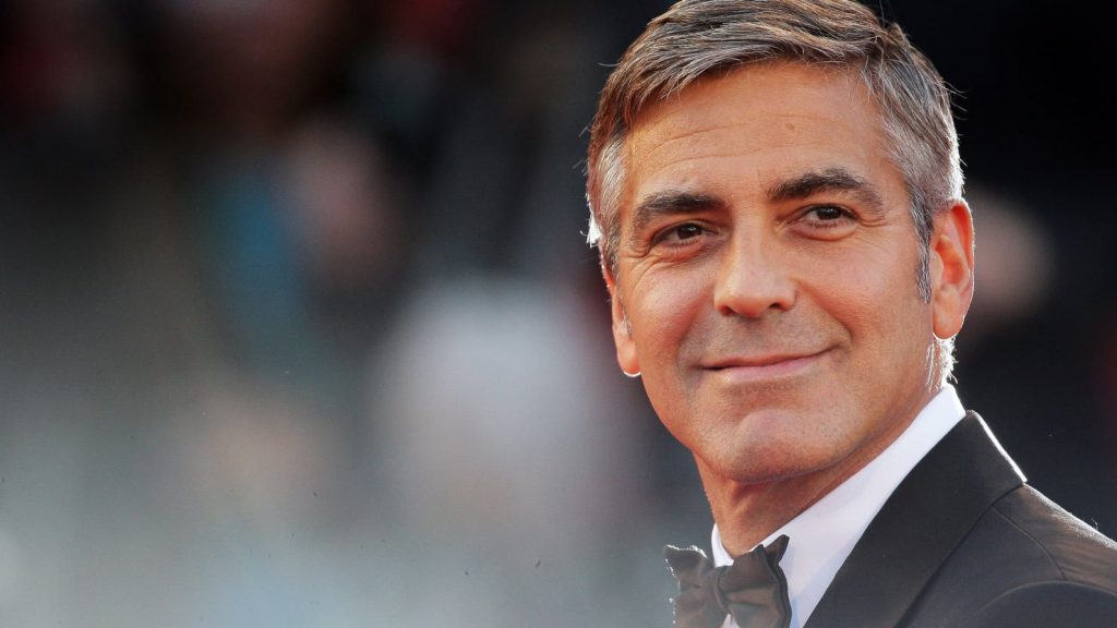 George Clooney se usmívá a hledí do dálky.