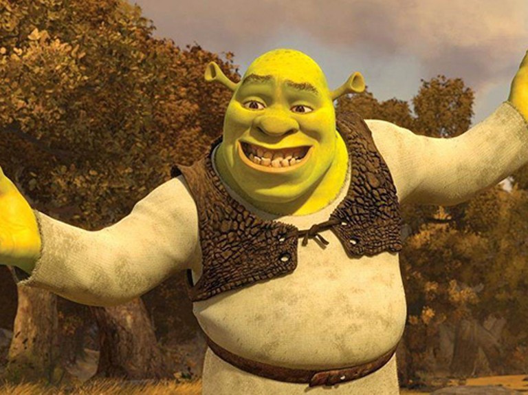 Shrek v lese rozpřahuje ruce a má křečovitý úsměv.