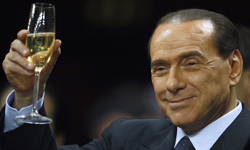 Silvio Berlusconi zvedá skleničku se sektem k přípitku. 