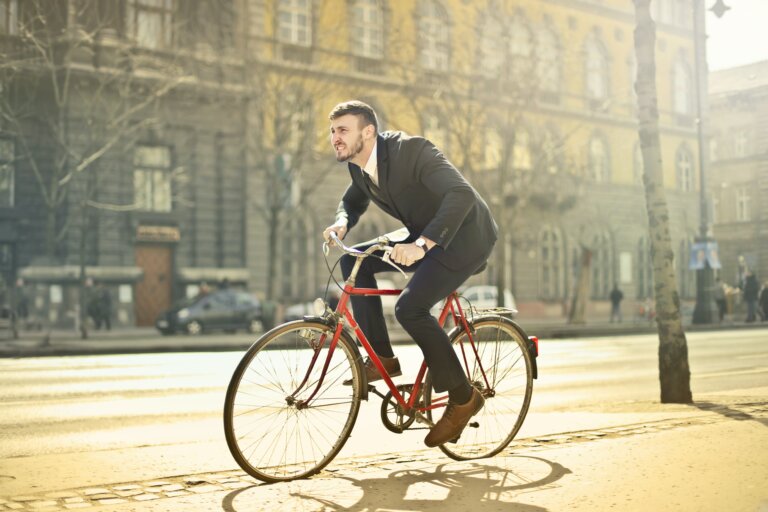 Muž jede ulicí města na červeném kole.